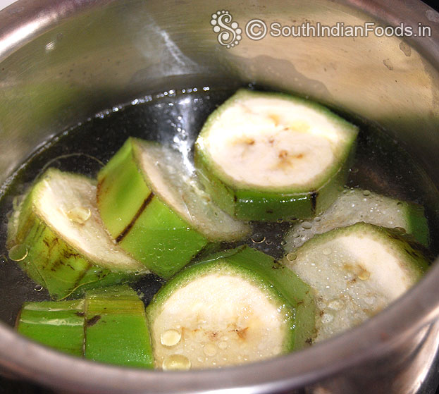 In a pan, add water, 1 tbsp oil and raw banana